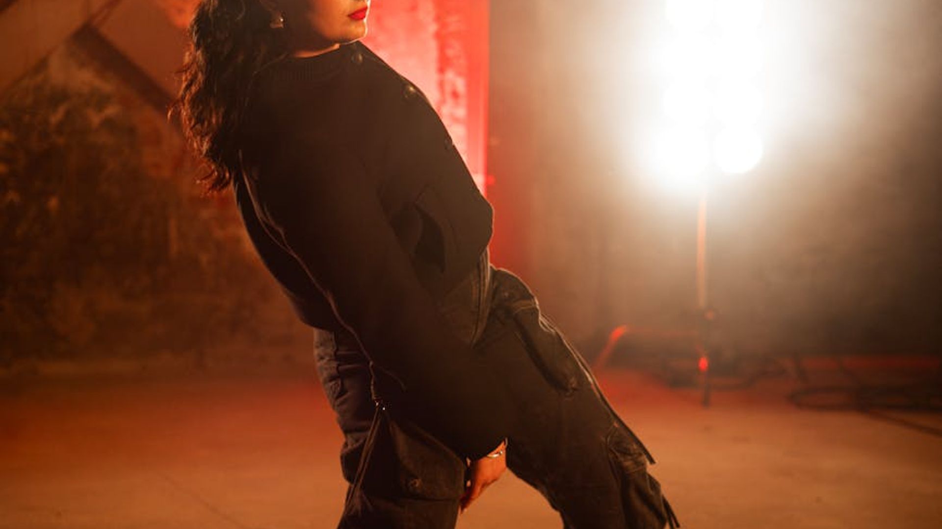 Person performing energetic cardio movements in a modern light studio.