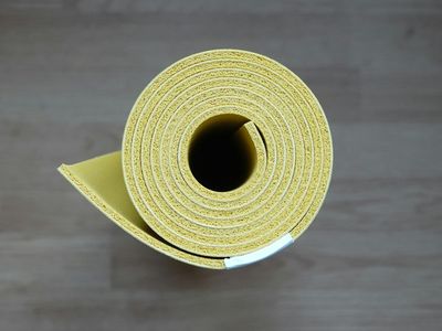 Yoga mat rolled up leaning against a white wall.